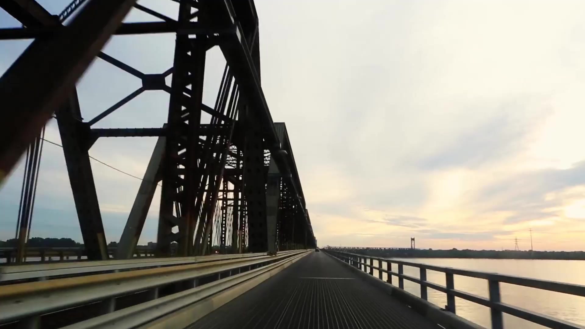Driving across a steel bridge at sunrise